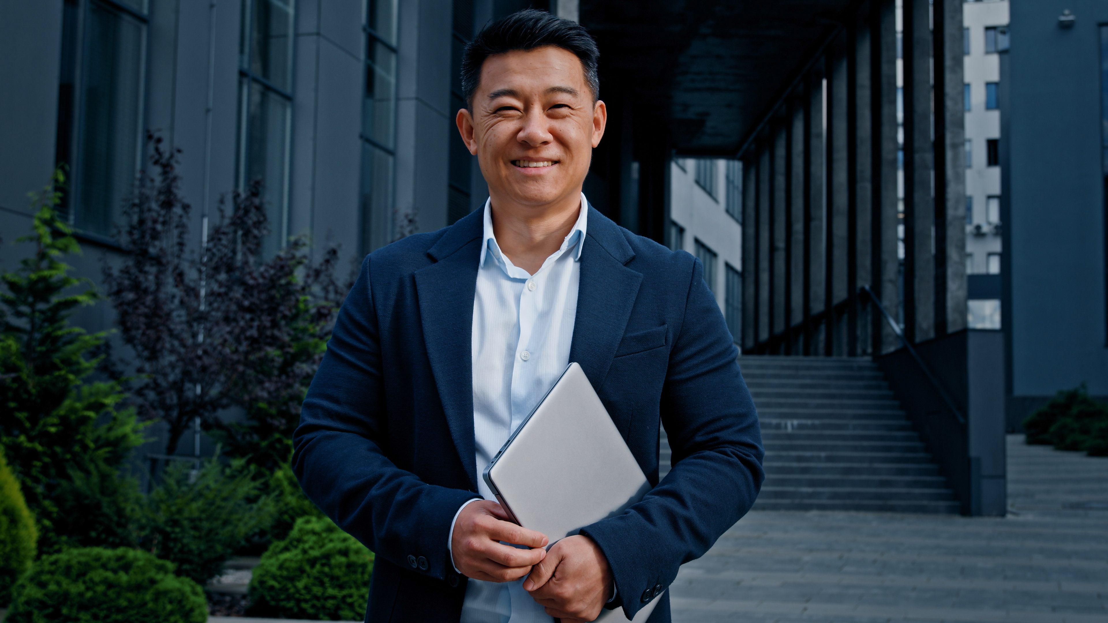 smiling-man-holding-laptop-in-urban-setting-2026-01-09-06-38-31-utc